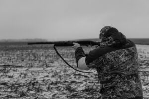 grayscale photo of person holding rifle